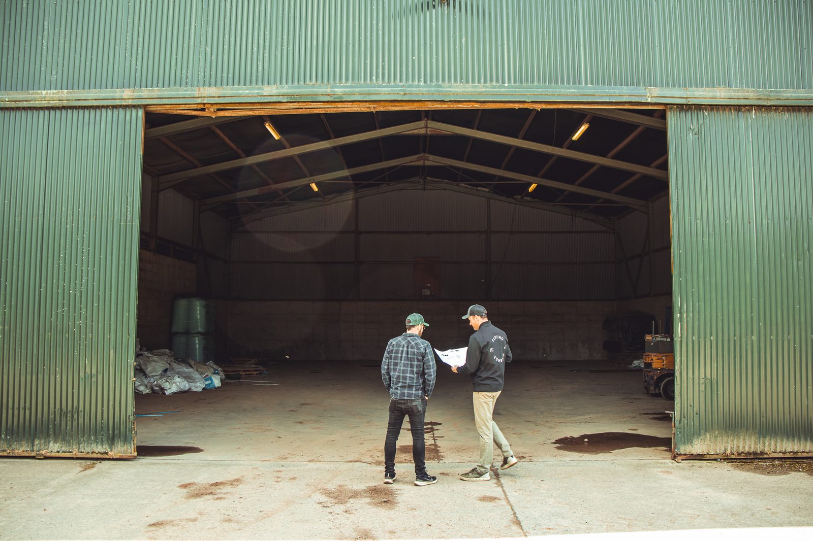 Two men with blueprints at the shed